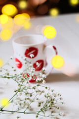 Cup of tea with flower on the table. Bokeh lights. Celebration atmosphere. Retro style, vintage toned.