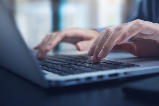 Close up image of woman hands typing on laptop computer keyboard and surfing the internet on office table