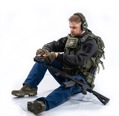 Fototapeta premium airsoft player in full gear with guns GG RK74. a man in headphones, a bulletproof vest, with a backpack and a belt walks on and aims his machine gun at the target. isolated, white background.