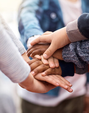 Friends stick together. Shot of a group of unrecognizable elementary school kids joining their hands together in a huddle.
