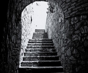 Escalera antigua bajo arco de piedra &ndash; transici&oacute;n entre sombras y luz