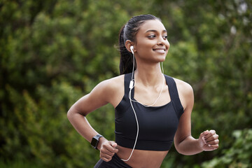 I know where Im going. Shot of a sporty young woman wearing earphones while running outdoors.