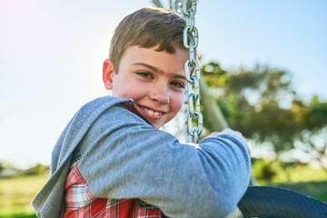 Want to see how high I can swing. Portrait of a young boy sitting on a swing in a park.