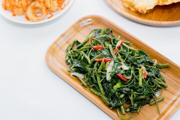 Processed kale. Served on a wooden plate. Cah Kangkung.