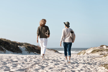 Heading out to find the perfect spot. Rearview shot of two unrecognizable woman walking with their...