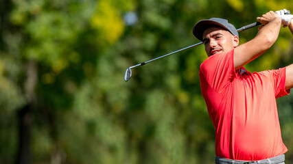 Young golfer in a red shirt playing golf, hitting a ball, convenient copy space