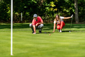 Obraz premium Young couple on a golf course, reading green