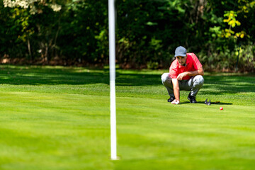 Obraz premium Young golfer playing golf on a beautiful sunny day, reading green