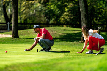 Obraz premium Young couple on a golf course, reading green