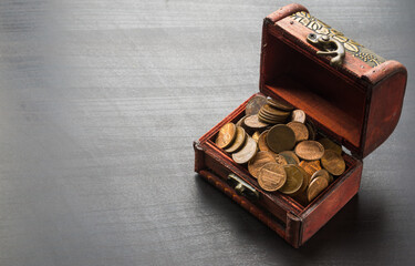 Old coins in vintage small wooden chest on black table