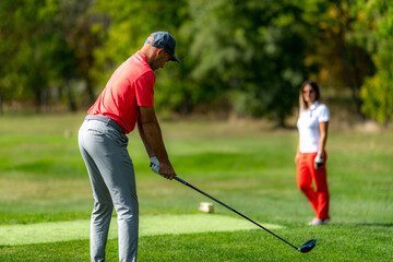 Young couple on a golfing vacation, man teeing off