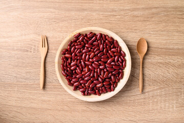 Red kidney bean on plate with spoon and fork on wooden background, Table top view