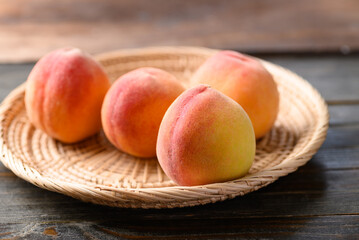 Peach fruit in basket on wooden background