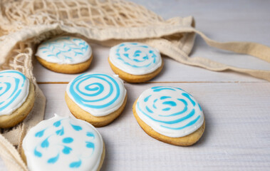 Gingerbread in the shape of eggs and rabbits on a white wooden table, eco bag and flowers, the concept of preparation for Easter