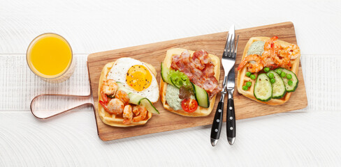 Breakfast waffles with fried eggs, salmon, cucumber and prawns