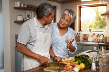 Making their retirement a delicious one. Shot of a happy mature couple drinking wine while cooking...