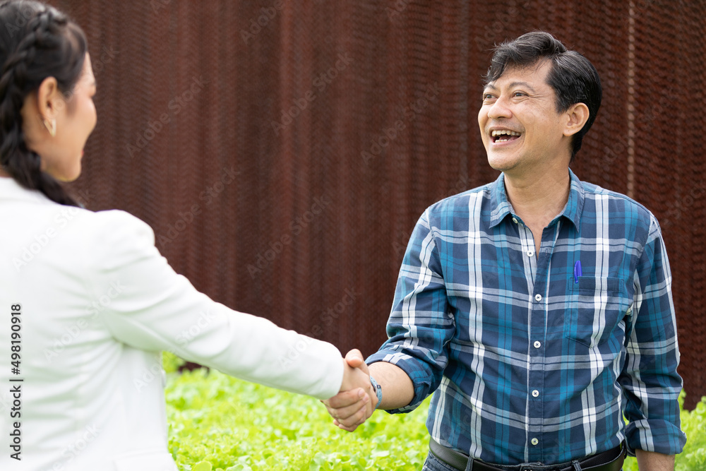 Wall mural male farmer shaking hands businesswoman together in hydroponic farm