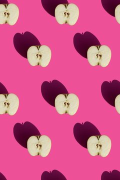 seamless pattern of halves of apples on a pink background with hard sunlight. High quality photo