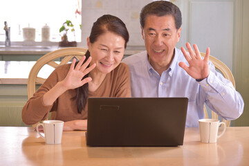 笑顔で孫とインターネット通話をするシニア夫婦