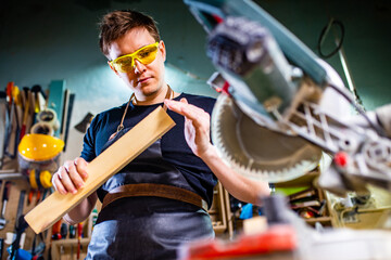 Fototapeta na wymiar Portrait of handsome carpenter working with plank in workshop