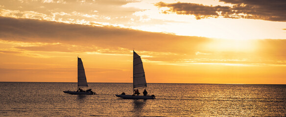 two sailboats in sunset sea