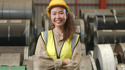 Asian industrial woman curly hair engineer standing wearing safety uniform with hardhat smiling and...