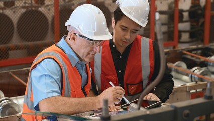 Engineer teaching apprentice to use metal sheet stamping machine, industrial team is working on...