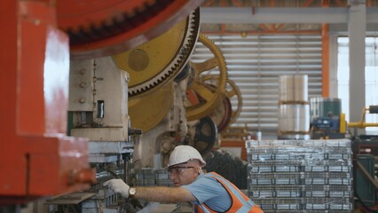 Engineer or operator wearing a safety suit working bending metal sheet by sheet press bending...