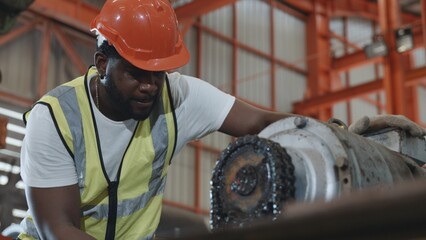 Engineer or operator wearing a safety suit maintaining machine in the industrial factory, service technicain worker operating tighten the nut repair machinery at metal sheet factory