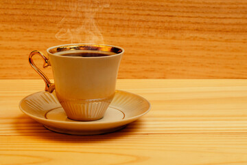 Coffee cup with brewed coffee and steam on a wooden surface
