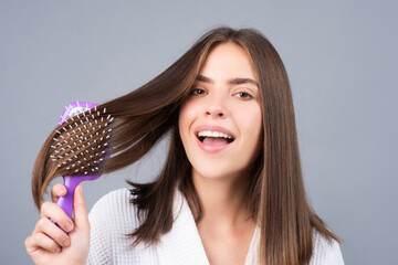 Amazed woman combing hair. Close up portrait of female model with a comb brushing hair. Girl with...