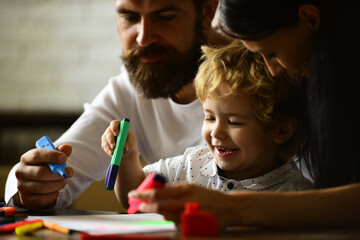 Happy family mother father and child son drawing laughing. Early childhood education, kids creative growth. Parents and their little child painting writing in book with pencil making homework at home.