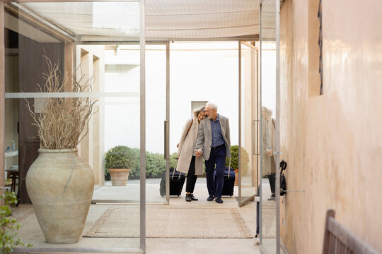 Senior couple with suitcases walking at boutique hotel