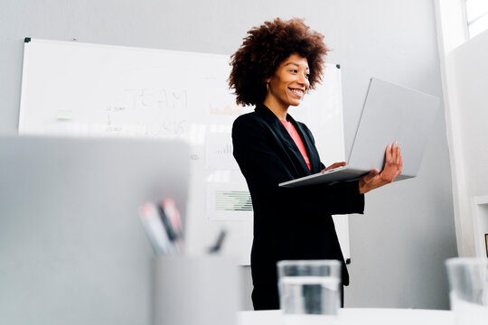 Happy businesswoman with laptop standing in front of whiteboard