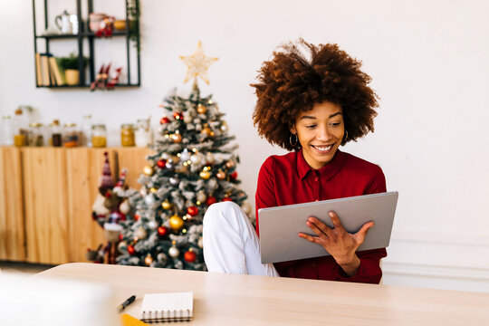 Happy young woman using tablet PC sitting in living room at home