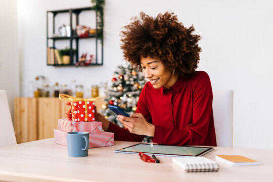 Smiling young woman using mobile phone at home