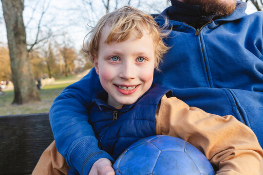 Smiling son with father sitting on bench at park