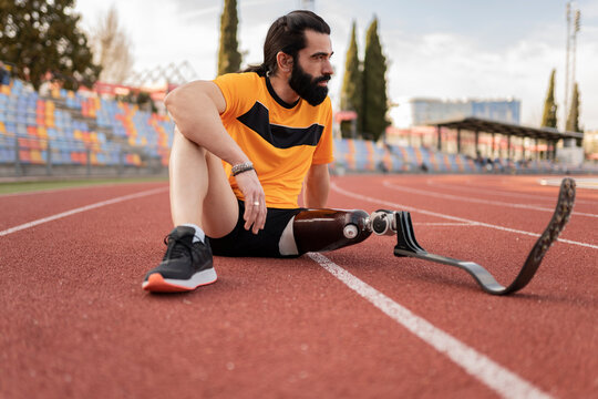 Athlete with prosthetic leg sitting on running track