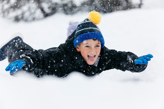 Playful boy sticking out tongue lying on snow