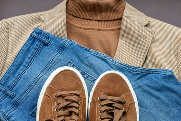 Men brown suede brogue shoes combined with light beige blazer, blue jeans and belt. Top view.