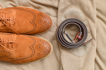 Men brown suede brogue shoes combined with light beige blazer and belt. Top view.