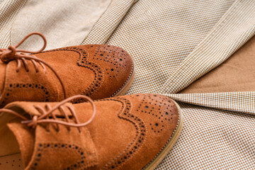 Men brown suede derby shoes combined with light beige blazer. Selective focus.