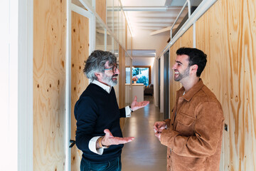 Happy senior man gesturing talking with cheerful son at home