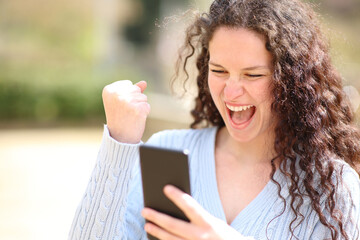 Excited woman celebrating news checking smartphone