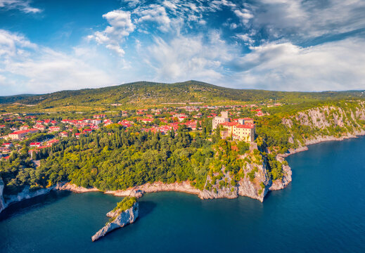 Bright  summer view from flying drone of Duino Castle. Wonderful morning scene of Adriatic coast of Italy, Europe. Beautiful cityscape of Duino town. Traveling concept background..