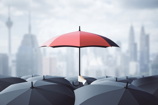 Businessman hand holding red umbrella over crowd on blurry dull city background. Risk, protection and safety concept.