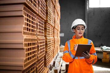 Female factory worker checking inventory of building blocks for construction industry.