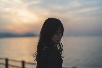 Fototapeta premium 夕暮れの海沿いで散策する女性