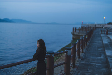 夕暮れの海沿いで散策する女性