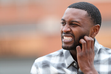 Man with black skin scratching itchy beard